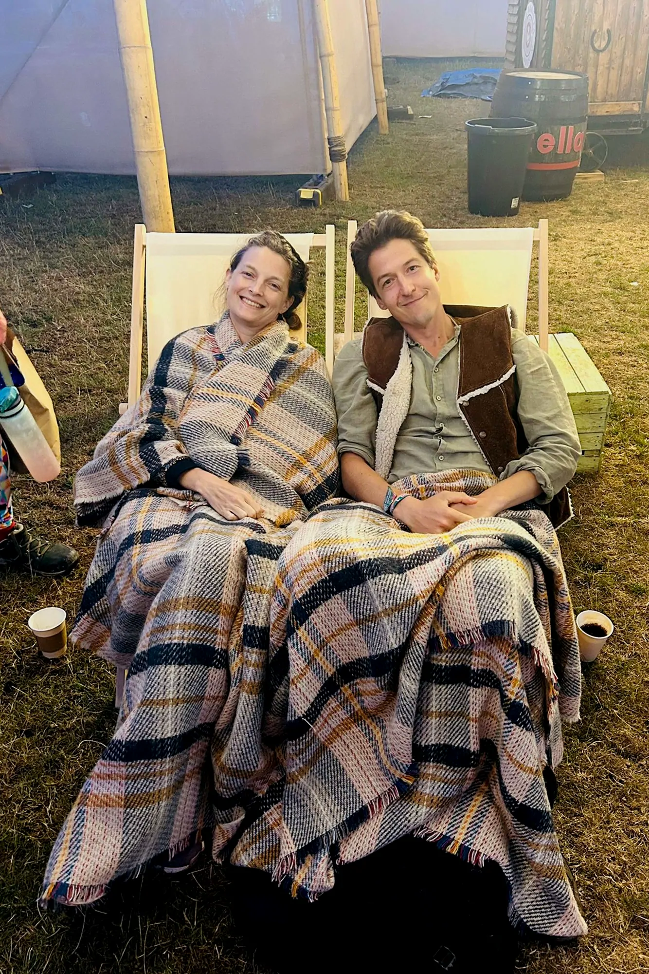 Anton and Morgane wrapped in blankets in deckchairs under a marquee